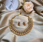 Antique gold-plated necklace with Lakshmi coin motifs. Ruby and emerald-toned accents for vibrant appeal.