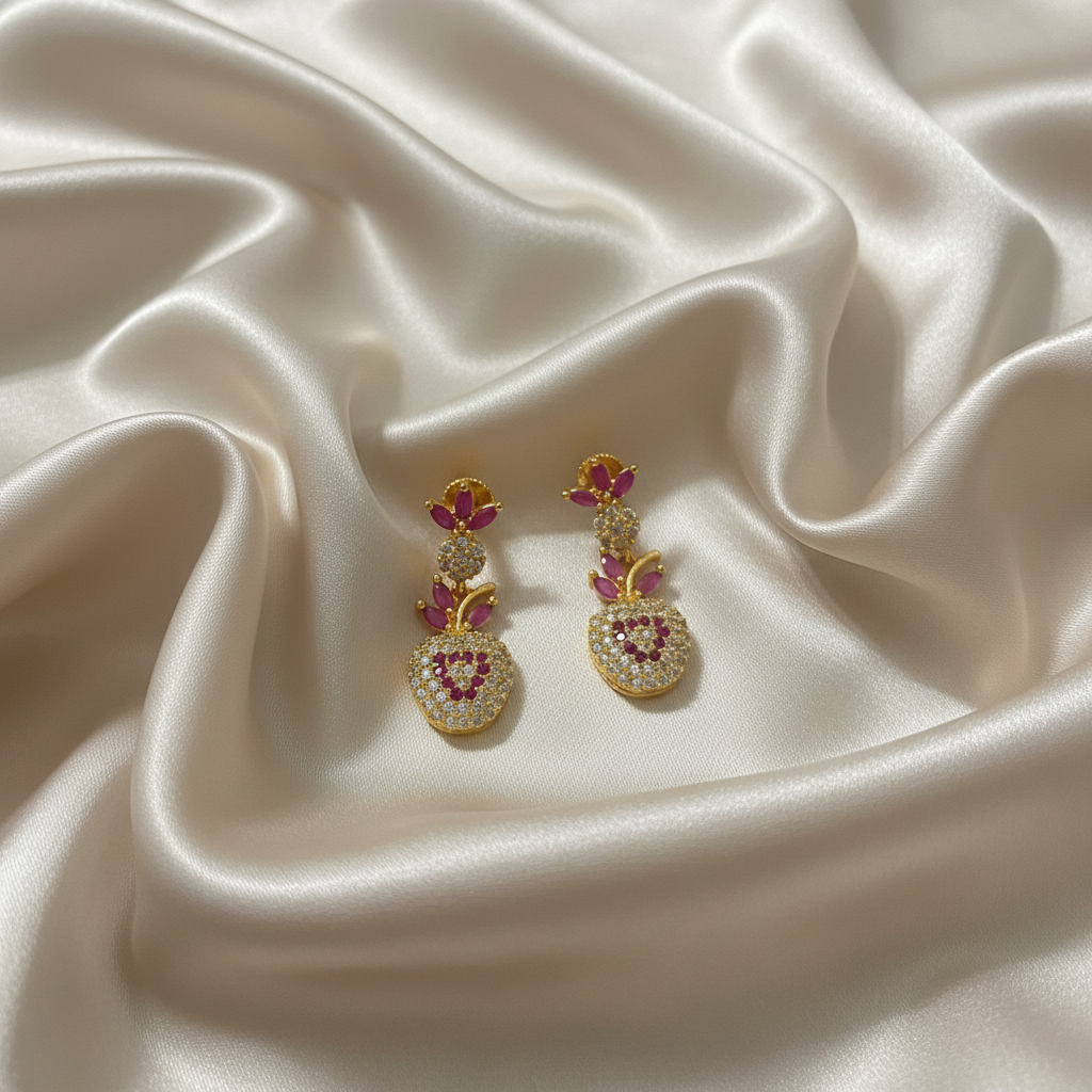 Gold earrings with pink gemstones on satin fabric